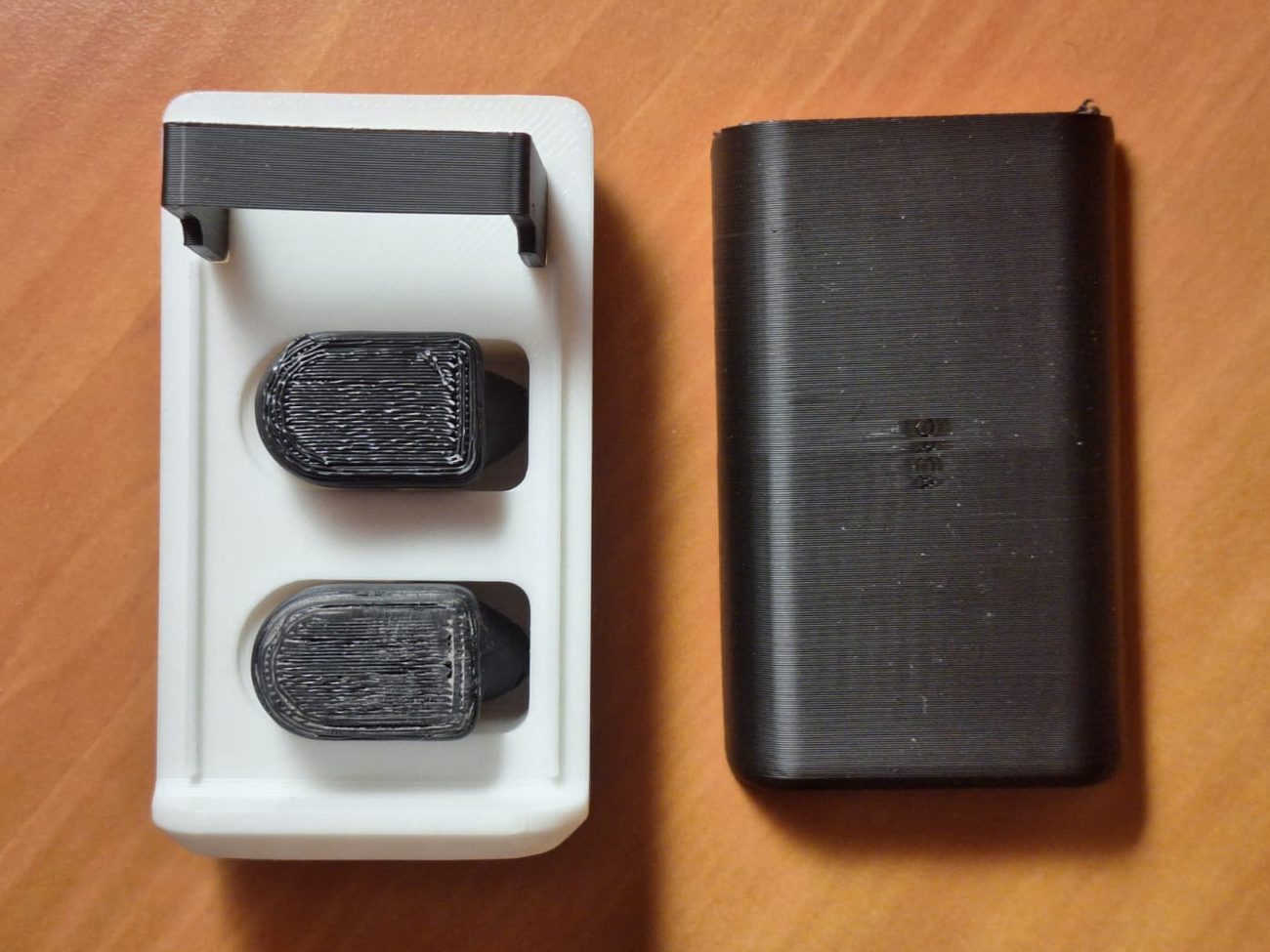 First ONYX prototype: a white 3D printed tray holding two black earbuds, next to its black sliding cover