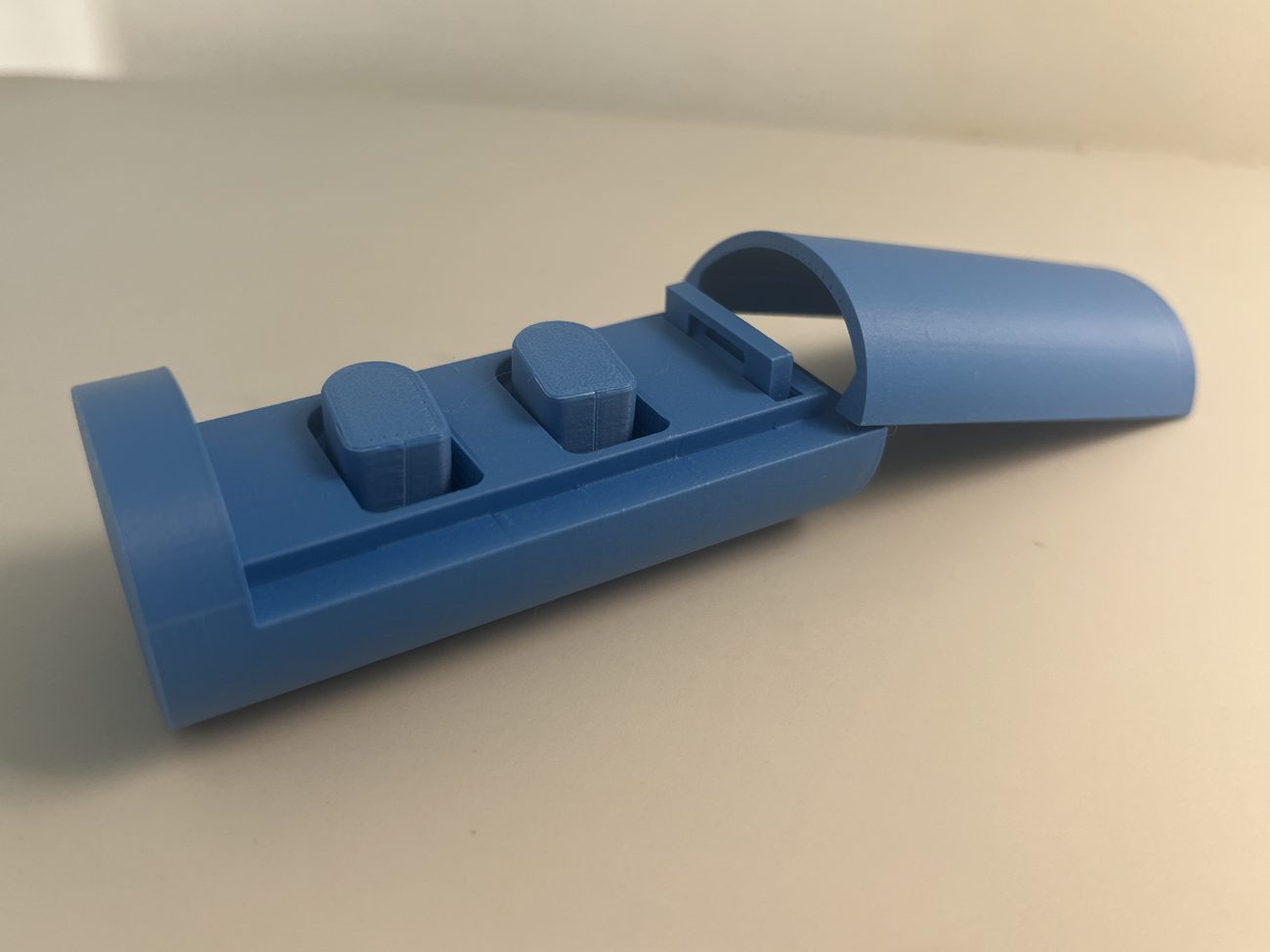 Second ONYX prototype: a blue 3D printed case with its cover lifted open, showing two earbuds in the tray